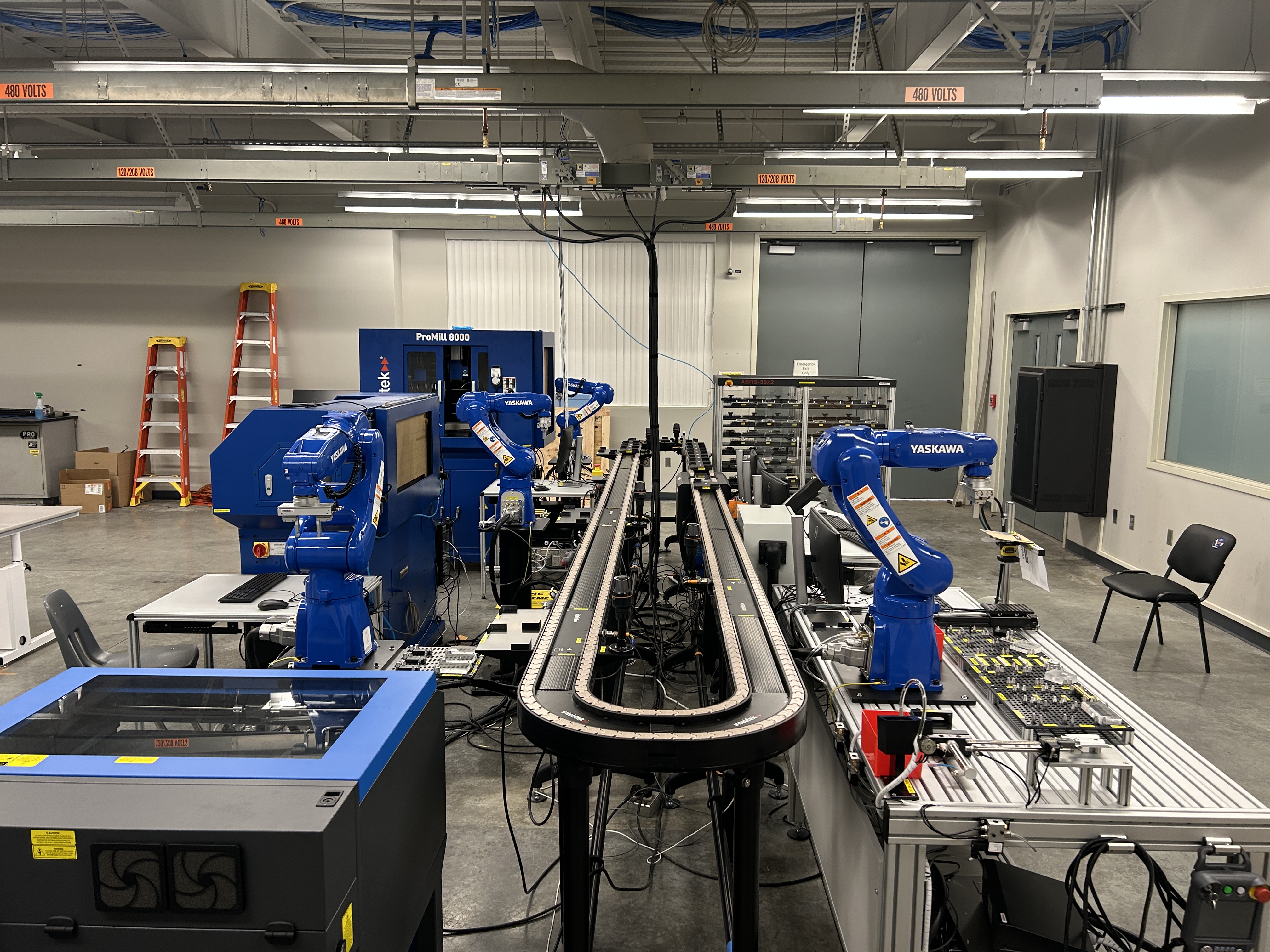 A specialized university automation lab with multiple industrial robots, conveyors, and manufacturing equipment