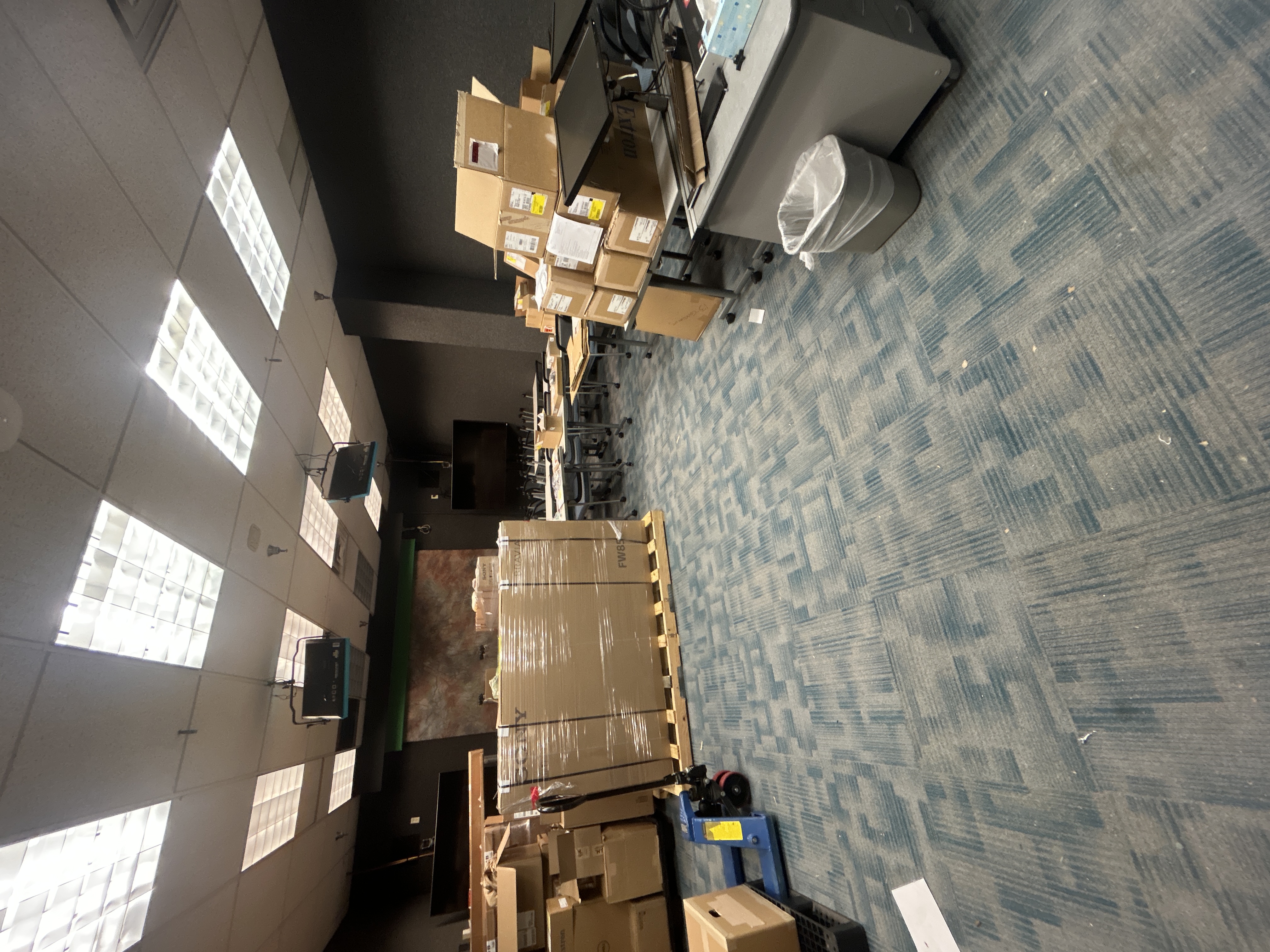 Palletized displays and boxed equipment staged for a large classroom technology deployment