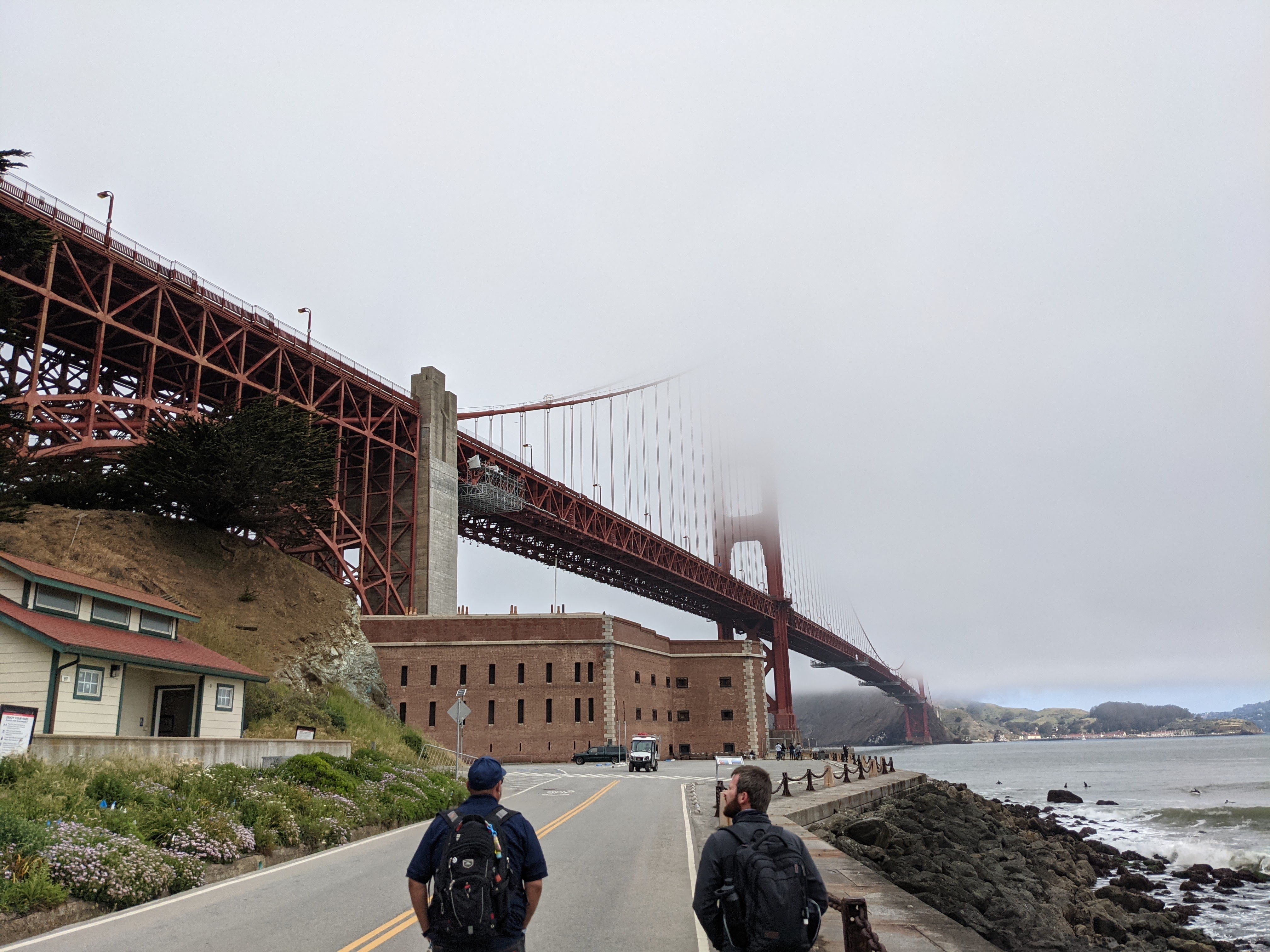 Two people walking through a foggy coastal site survey area