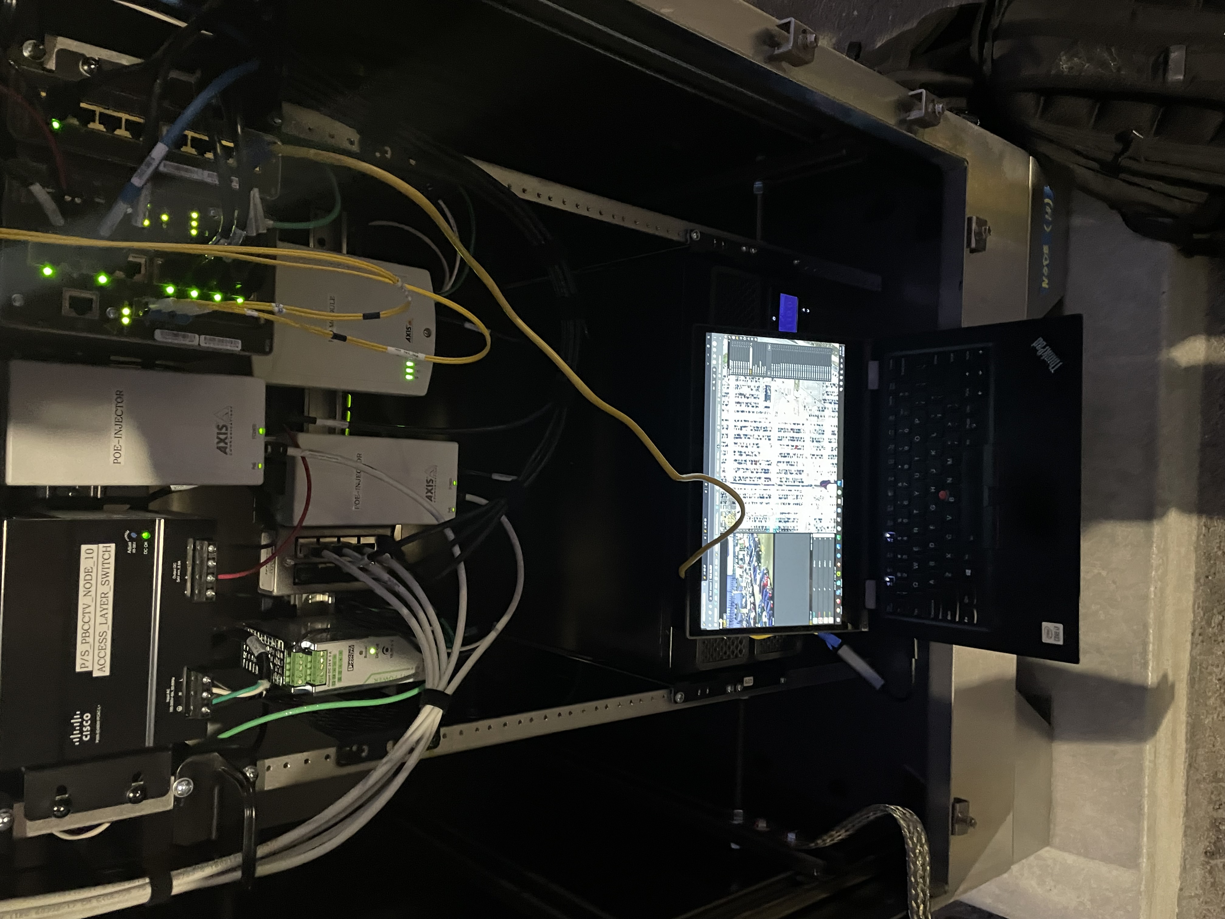 A laptop connected to networking and PoE equipment during on-site commissioning